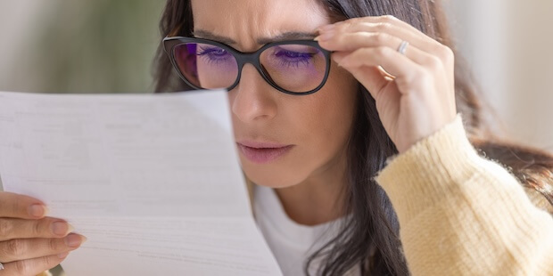 Frau liest angestrengt Schreiben vom Amt - Symbolbild für das Thema Renteninformation verstehen AB