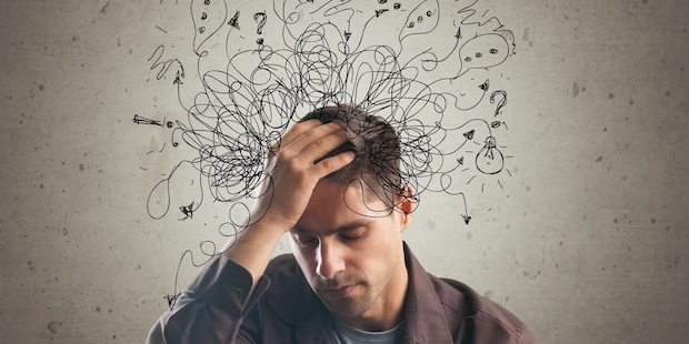 Ein gestresster Mann sitzt mit geschlossenen Augen, während chaotische Skizzen über seinem Kopf innere Anspannung, Grübeln und mentale Überforderung darstellen